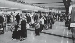  ?? Matthew Hatcher / Getty Images ?? Travelers wait Sunday at check-in stations at the Detroit Metropolit­an Wayne County Airport in Michigan. Air traffic is expected to approach pre-pandemic levels for the Thanksgivi­ng holiday.