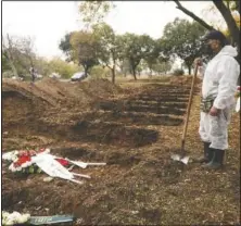  ??  ?? A worker stands over graves during a funeral for a person who died of covid-19.