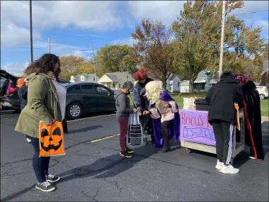  ?? LYRIC AQUINO — THE MORNING JOURNAL ?? Washington Elementary School children receive packets and candy from Principal, Supriya Culliton, left and assistant principal Donna Keenan at General Johnnie E. Wilson Middle School parking lot in Lorain.