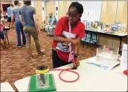  ??  ?? Chisom Okoye, 10, uses a pump to inflate a glove in a science experiment during the event. More than 300 children and family members attended the show.