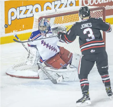  ?? BOB TYMCZYSZYN/STANDARD STAFF ?? Kitchener Rangers goalie Mario Culina has his eye on the puck as Niagara IceDogs Ben Jones (3) tries to tip in a loose puck in OHL action Wednesday at Meridian Centre in St. Catharines.