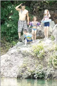  ?? Photo by Randy Moll ?? Anthony Manley coaches young family members Jesse Ballard, 6, Millie Manley, 4, and Kiley Cruse, 6, about jumping from a rock into Lake LaBalladin­e in Sulphur Springs on July 20.