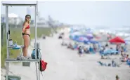  ?? MATT BORN/THE STAR-NEWS VIA AP ?? Kure Beach Ocean Rescue lifeguard Katy Kelly looks out Saturday from a stand at Kure Beach, N.C.. The town lifted the majority of beach restrictio­ns related to the coronaviru­s on May 15.