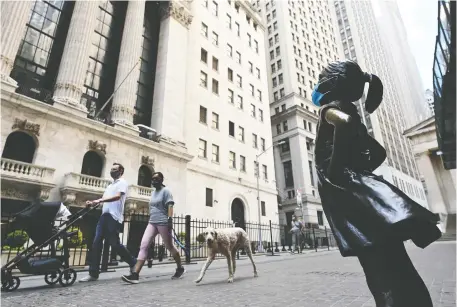  ?? JOHANNES EISELE/AFP VIA GETTY IMAGES ?? People walk past a masked Fearless Girl sculpture in front of the New York Stock Exchange. As markets slowly come out of the pandemic shutdown, there are some massive deals out there which would light a fire under Wall Street.