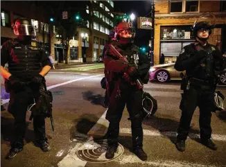  ?? PAULA BRONSTEIN / AP ?? Portland police stand guard Saturday, on a night when one person was killed as a caravan of President Donald Trump supporters and Black Lives Matter protesters clashed in the streets.