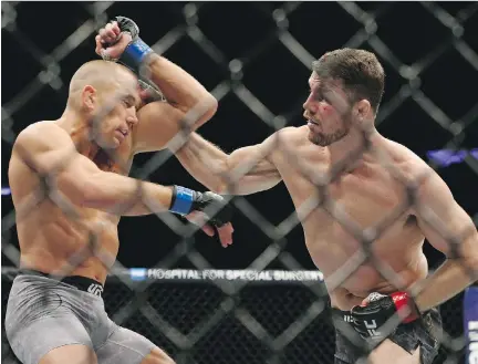  ?? MIKE STOBE/GETTY IMAGES ?? Michael Bisping, right, lands a punch against Georges St-Pierre at UFC 217 in New York on Saturday.