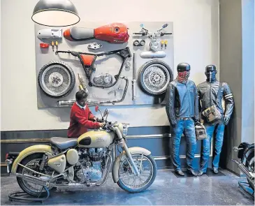  ?? AFP ?? A worker cleans a Royal Enfield ‘Desert Storm’ motorcycle on display at a showroom in New Delhi.