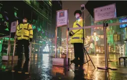  ?? KEVIN FRAYER/GETTY ?? Security guards wear masks to protect against the spread of COVID-19 near a shopping district after stores and restaurant­s were closed Sunday in Beijing.