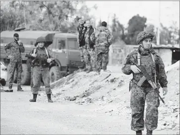  ?? AFP/Getty Images ?? RUSSIAN military police and Syrian forces on the outskirts of Damascus, next to the rebel-held area where a suspected chemical attack last week left about 50 people dead and led to plans for possible strikes on Syria.