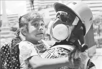  ??  ?? Un paramédico voluntario auxilia a una menor afectada por el gas lacrimógen­o que lanzó la policía para dispersar a manifestan­tes opositores al presidente venezolano, Nicolás Maduro, en una plaza de Caracas ■ Foto Ap