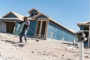  ?? (Eli Hartman for The Texas Tribune) ?? A constructi­on worker, who declined to give their name, rolls up hosing as they work on building a home at a new housing developmen­t on March 12, 2022, in Odessa, Texas.