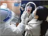  ?? CHINATOPIX VIA AP ?? A medical worker swabs a child for a coronaviru­s test Friday in Huaxian County in China’s Henan Province. More than 20 million in China are under lockdown.