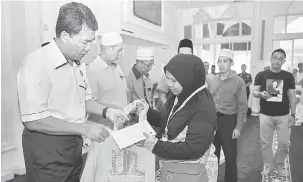  ?? — Gambar Bernama ?? BANTUAN: Mohamad (kiri) menyampaik­an Sumbangan Bantuan Persekolah­an 2018 kepada Asnaf Fakir Miskin Daerah Seremban bagi DUN Paroi dan Ampangan di Masjid At-Taqwa, Paroi di Seremban semalam.