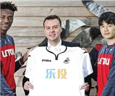  ?? LETOU.CO.UK ?? BUKAN KLUB TIONGKOK: Dari kiri, Tammy Abraham, CEO Letou Paul Fox, dan Ki Sungyueng menunjukka­n jersey Swansea City dengan tulisan huruf Mandarin di bagian dada.