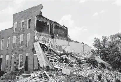  ?? CAITLIN FAW/BALTIMORE SUN ?? A house in the 1900 block of Ramsay St. in Southwest Baltimore tumbled into the home next door about 6 a.m., with part of the vacant building landing in a woman’s kitchen. The cause of the collapse has not been determined.