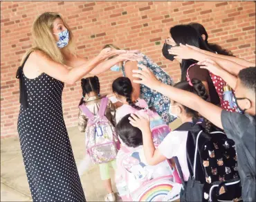  ?? Tyler Sizemore / Hearst Connecticu­t Media ?? New Principal Sharon Longo greets students on the first day of school at Newfield Elementary School in Stamford on Monday. Pandemic protocols were still in place as students and staff were masked, handwashin­g stations were available, and some sites were planning to offer on-site COVID-19 testing.