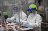  ?? PHOTO COURTESY SMITHFIELD FOODS ?? On May 20, workers inside a Sioux Falls, South Dakota, pork processing plant wear protective gear and are separated by plastic partitions as they carve up meat.