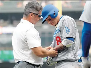  ?? Abbie Parr Getty Images ?? MANNY MACHADO of the Dodgers gets his wrist examined after being hit by a pitch in the ninth inning Sunday. Machado was hit by Seattle infielder Andrew Romine, who had taken over pitching duties.