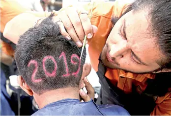  ??  ?? A man applies colour to a haircut with the number ‘2019’, depicted to welcome the new year at a barbershop in Ahmedabad, India. — Reuters photo
