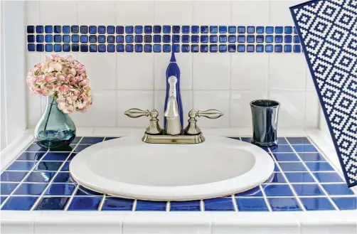  ??  ?? A band of tile in Classic Blue can provide an accent to a plain white backsplash. Pair the look with the countertop and accessorie­s to add color to a bathroom.