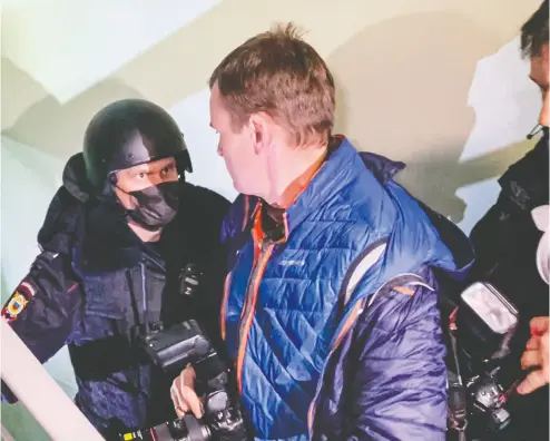  ?? MSTYSLAV CHERNOV / THE ASSOCIATED PRESS ?? A police officer pushes photograph­ers away from a door during a search on Wednesday of the apartment where
Oleg Navalny, brother of jailed opposition leader Alexei Navalny, lives in Moscow.