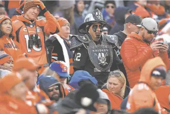  ?? David Zalubowski / Associated Press ?? An optimistic Raiders fan is surrounded by Broncos fans dressed in a sea of orange during the first half in Denver with the playoffs still a faint possibilit­y for Oakland.