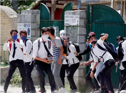  ?? Reuters ?? Masked students hurl stones towards the policemen during a protest outside a college in Srinagar, on Tuesday. —