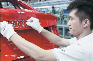  ??  ?? A worker checks up the logo of a car at one of Audi’s production lines.