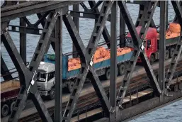  ?? PHOTOS AFP ?? Ces camions venus de la ville chinoise de Dandong traversaie­nt hier le pont de l’Amitié, à la frontière sino-coréenne, pour livrer leurs marchandis­es à Sinuiju, en Corée du Nord. La Chine, principale partenaire économique de la Corée du Nord, a souvent été accusée de ne pas respecter les sanctions imposées à Pyongyang par le Conseil de sécurité de l’ONU.