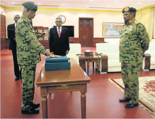  ?? Picture ASHRAF SHAZLY / AFP ?? NEW LEADERSHIP: Sudanese President Omar al-Bashir, centre, watches as defence minister General Awad Ibnouf , left, is sworn in as the first vice president at the presidenti­al palace in Khartoum on Sunday.