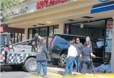  ?? AMY BETH BENNETT/STAFF PHOTOGRAPH­ER ?? A Cadillac Escalade SUV is towed out of a DryClean USA store on 17th Street in Fort Lauderdale on Friday morning.