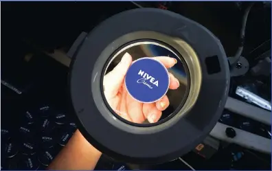  ??  ?? An employee examines a Nivea skin cream cover during a quality control inspection on a production line.