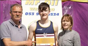  ??  ?? Jack Forde of St. Killian’s, athlete of the month for March, receives his award from Paddy Morgan, Chairman of Wexford Athletics, and Marie Mooney of Mr Oil (sponsors).