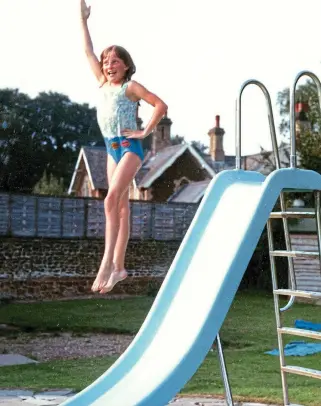  ??  ?? Exuberant: Always a keen swimmer and with her bathing suit stitched with her proficienc­y badges, Diana jumps off the slide at the pool at Park House