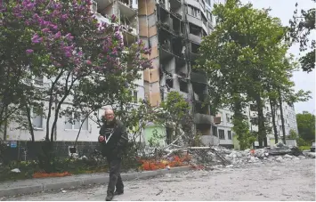  ?? SERGEY BOBOK / AFP ?? A man walks past a badly damaged building Saturday in Kharkiv, which was the target of an earlier unsuccessf­ul push by Russian troops.