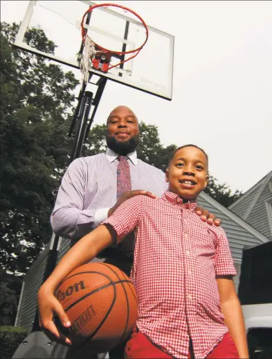  ?? Christian Abraham / Hearst Connecticu­t Media ?? Stacey Pierre-Louis and his son Eliah, 9, at their home in Trumbull on Friday. Captured on n a home security video, Eliah could be seen momentaril­y hiding from a Trumbull police cruiser when he was playing basketball in his driveway. Stacey posted the video on Instagram on June 11 and it has garnered 65 million views online.