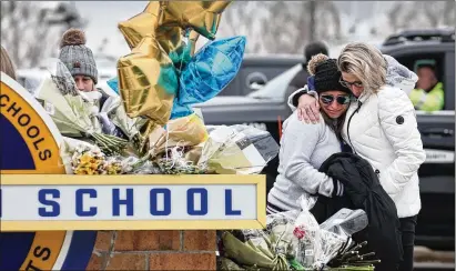  ?? SCOTT OLSON/GETTY IMAGES/TNS ?? People visit a makeshift memorial outside of Oxford High School on Wednesday in Oxford, Michigan. Four students were killed and seven people were injured Tuesday when a gunman opened fire at the school.