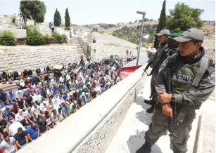  ?? (Marc Israel Sellem/The Jerusalem Post) ?? AS POLICE SECURE the scene, Muslims pray on July 20 near the Lions’ Gate to the capital’s Old City. The worshipers refused to ascend the Temple Mount in protest against the placement of metal detectors following a terrorist attack six days earlier.