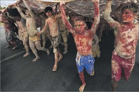  ?? Eraldo Peres Associated Press ?? INDIGENOUS people, painted with red ink representi­ng spilled blood and clay representi­ng gold, protest mining activities in Brasilia.