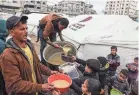  ?? SAID KHATIB/AFP VIA GETTY IMAGES ?? Volunteers distribute rations of red lentil soup to displaced Palestinia­ns in Rafah in the southern Gaza Strip on Sunday.