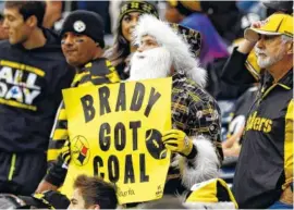  ?? THE ASSOCIATED PRESS ?? Santa Claus (a Pittsburgh Steelers fan) shows what New England Patriots quarterbac­k Tom Brady received for Christmas.