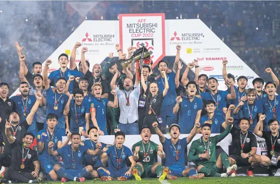  ?? REUTERS ?? Thailand coach Mano Polking lifts the trophy as he celebrates with his players and staff after winning the Mitsubishi Electric Cup at Thammasat Stadium on Monday.