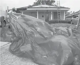  ?? GRANGER/THE TIMES-PICAYUNE/THE NEW ORLEANS ADVOCATE CHRIS ?? Donrell Breaux helps install a temporary roof on a home Wednesday in New Orleans East.