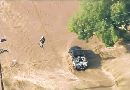  ?? KTLA ?? VIDEO from KTLA shows a driver being rescued by a helicopter team from the Los Angeles County Fire Department during monsoonal weather in Acton on Thursday. Storms swept across the high desert and f looded the area, delaying train service and closing...