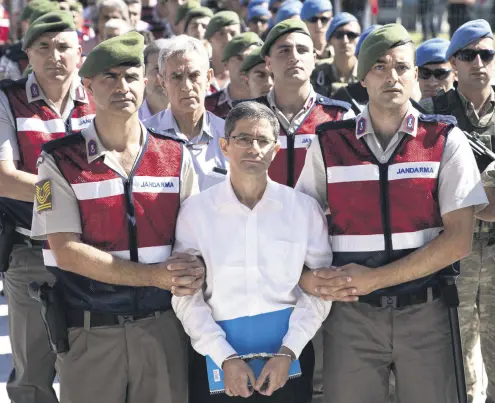  ??  ?? Kemal Batmaz being escorted by two gendarme officers, with former Air Force Commander Akın Öztürk right behind him.