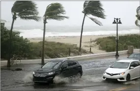  ?? JOE CAVARETTA — SOUTH FLORIDA SUN- SENTINEL VIA AP ?? Cars move along flooded highway A1A in Fort Lauderdale, Fla., on Sunday.