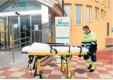  ?? MIGUEL ÁNGEL MOLINA / EFE ?? Un sanitario traslada una camilla en una residencia de Cájar (Granada), donde diez ancianos han fallecido.