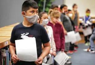  ?? Photos by Bob Owen / Staff photograph­er ?? Barrera Veterans Elementary School third-grader Matthew Gallegos holds his permission slip while awaiting a COVID-19 test.