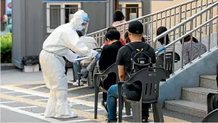  ?? AP ?? A South Korean health official wearing protective gear gives surveys to people waiting for the Covid-19 test at a public health centre in Goyang yesterday.