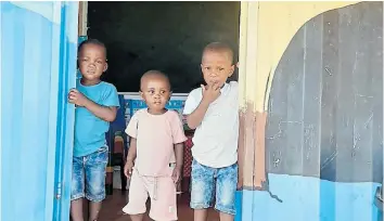  ??  ?? IN THE MOMENT: Three children peer out of one of theclassro­om Cameron helped fund at Ikamva ECD centre at Ndwayana Village near Peddie.
